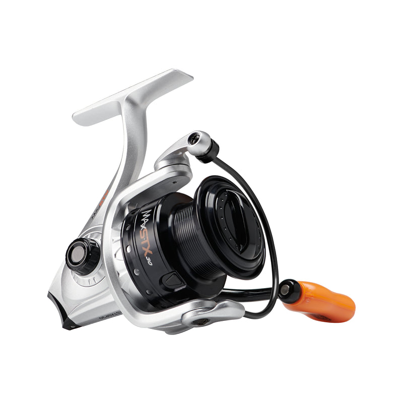 A modern Abu Garcia Max STX Spinning Reel featuring a sleek silver and black design with an orange accented handle knob. The reel is equipped with a black machined aluminum spool, a durable Everlast™ bail system, and clear Rocket Line Management™ markings on the body.